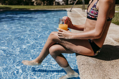 Midsection of woman sitting in swimming pool