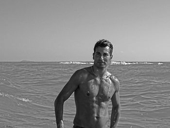 Portrait of shirtless man standing in sea against clear sky