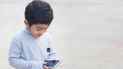 Rear view of boy using mobile phone