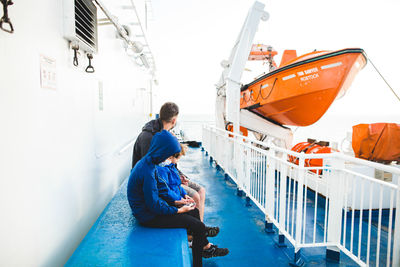 Men sitting on boat against blue sky