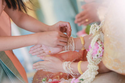 Midsection of woman performing rituals with bride and groom during wedding