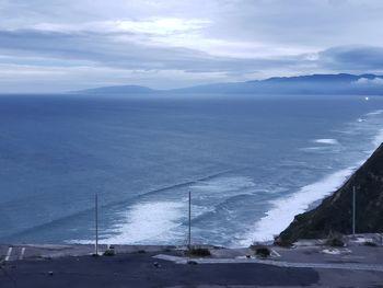 Scenic view of sea by snowcapped mountains against sky