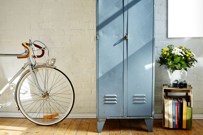 Bicycle by locker against wall at home