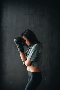 Side view of thoughtful boxer standing against black wall