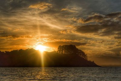 Scenic view of sea against cloudy sky at sunset