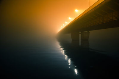 Low angle view of illuminated bridge over river at night