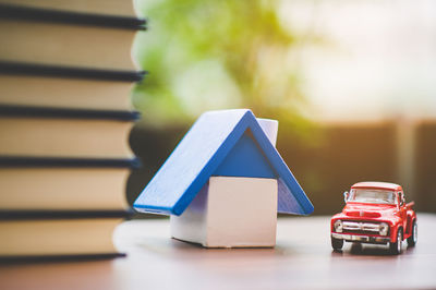 Close-up of model house and books with toy car on table