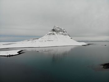 View of kirkjufjell mountain covered with snow over blue water in iceland