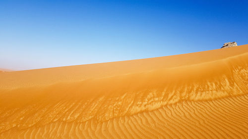 Sand dunes in desert against clear sky