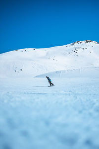 Person on snowcapped mountain against clear blue sky