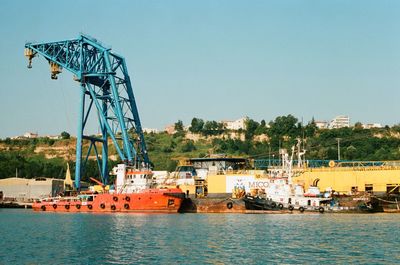 Cranes at commercial dock against clear sky