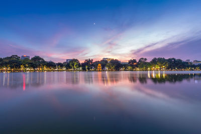 Scenic view of lake against dramatic sky at sunset