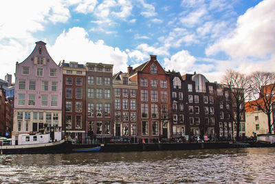 Buildings by canal against sky in city