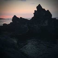 Rock formation on sea against sky during sunset