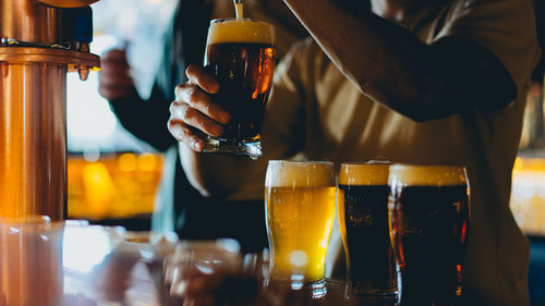 Close-up of man pouring beer in bar