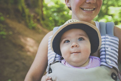 Midsection of smiling mother carrying son in baby carriage
