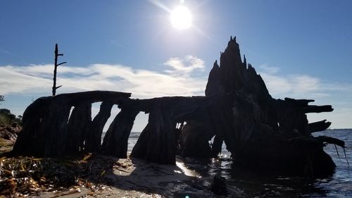 Driftwood on rocks by sea against sky