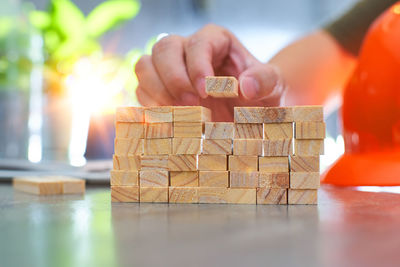 Cropped hands of women holding wooden block at table