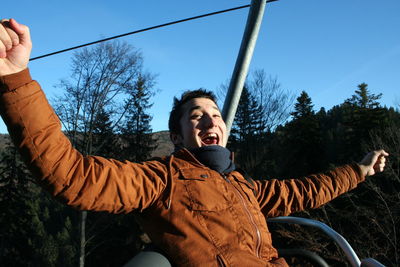 Low angle view of man holding umbrella against clear sky