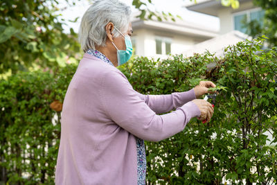 Side view of woman standing against plants