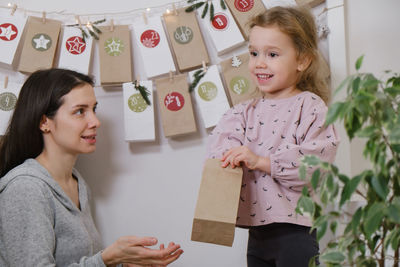 Mother with child opening christmas advent calendar tasks and gifts. toddler girl excited