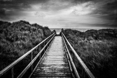 Boardwalk amidst landscape against sky