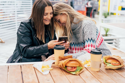 Portrait of woman using mobile phone while sitting on table