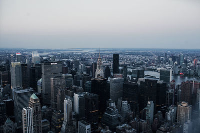 Aerial view of buildings in city against clear sky at sunset