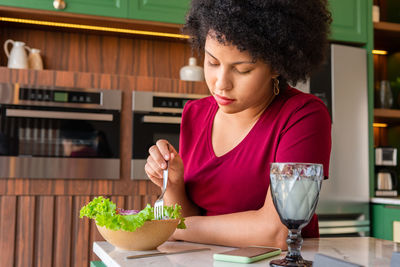 Young woman looking down while sitting on table