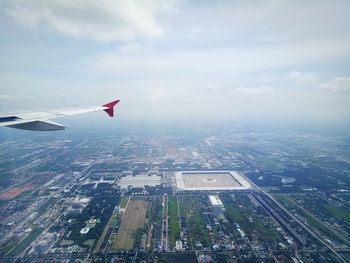 Airplane flying over cityscape against sky