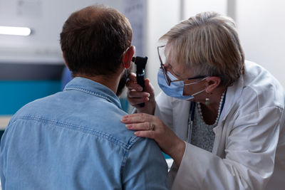 Doctor wearing mask examining patients ear