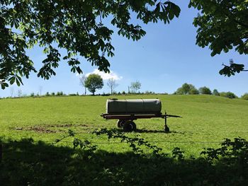 Water tank on grassy field against sky