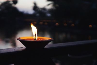 Close-up of lit diya against lake