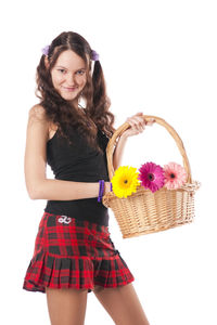 Beautiful young woman holding red flower in basket against white background