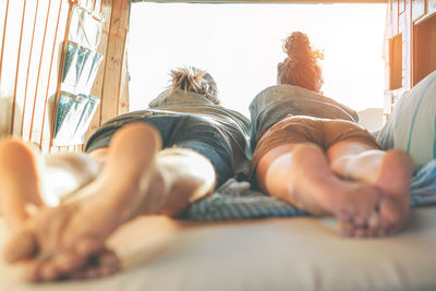 Rear view of couple lying on bed in caravan