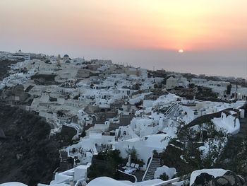 High angle view of snow covered buildings against sky during sunset