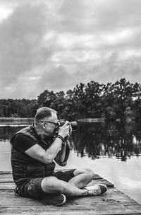 Man photographing at camera against sky