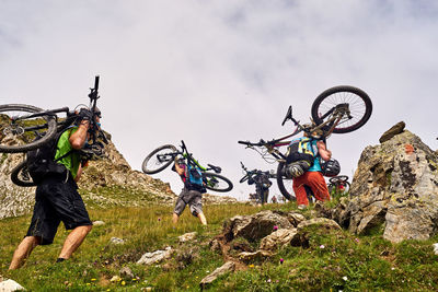 People by bicycle against sky