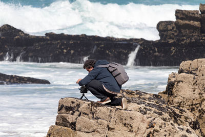 Man sitting on rock at beach