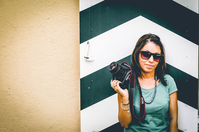 Portrait of young woman using mobile phone in city