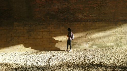 Full length of woman standing against wall