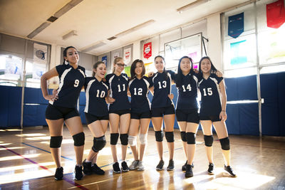 Front view of happy female volleyball team standing in court