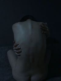 Rear view of shirtless woman against black background