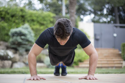 Rear view of man with arms outstretched against plants