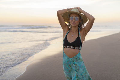 Smiling young woman with hat standing at beach