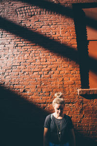 Woman 0standing against brick wall