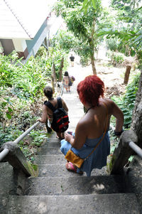 Rear view of shirtless friends on tree against sky