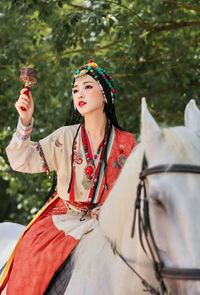 Portrait of smiling young woman with horse on field