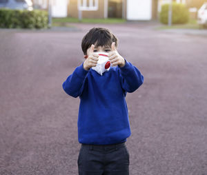 Portrait of boy holding ice cream standing outdoors