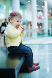 Cute girl eating food while looking away while sitting at mall